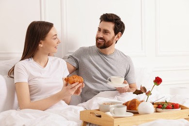 Photo of Happy couple having tasty breakfast in bed at home