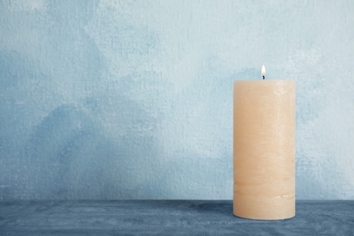 Photo of Alight wax candle on table. Space for text