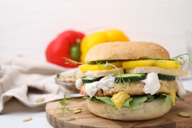 Photo of Tasty vegan burger with vegetables, sauce and patty on white table, closeup. Space for text