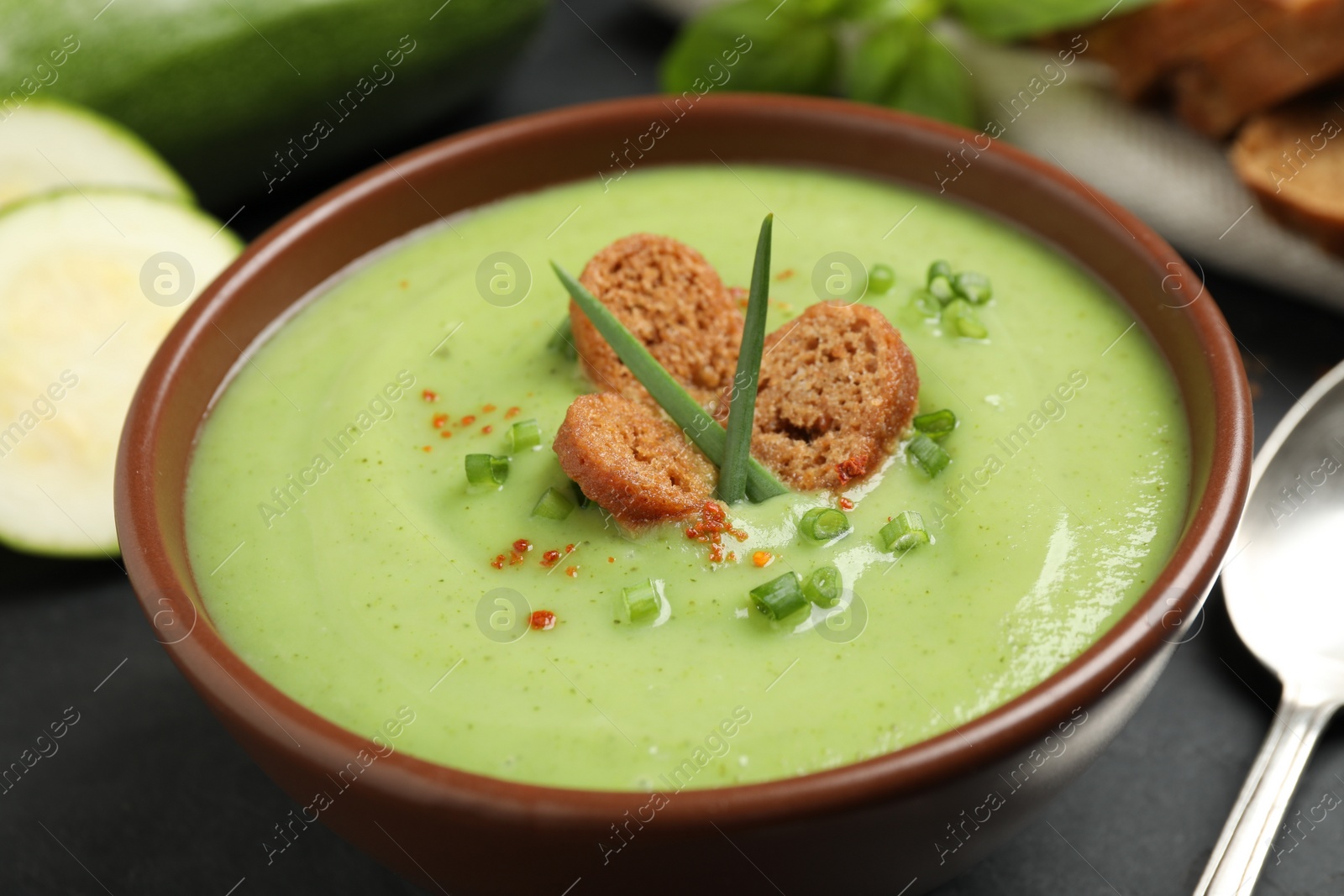 Photo of Tasty homemade zucchini cream soup in bowl on table, closeup