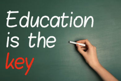 Image of Woman writing phrase Education is the key on chalkboard, closeup. Adult learning