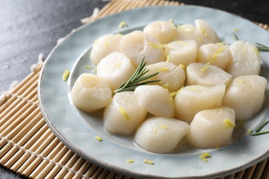 Photo of Raw scallops with lemon and rosemary on dark table, closeup