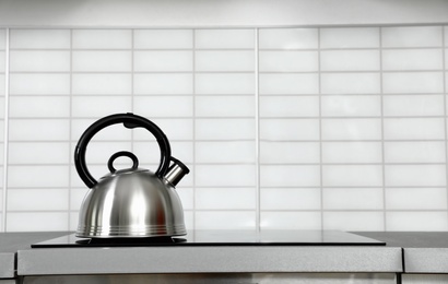 Modern kettle with whistle on stove in kitchen, space for text