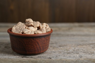 Bowl of tasty cod liver on wooden table, closeup. Space for text