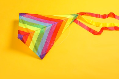 Photo of Bright rainbow kite on yellow background, top view