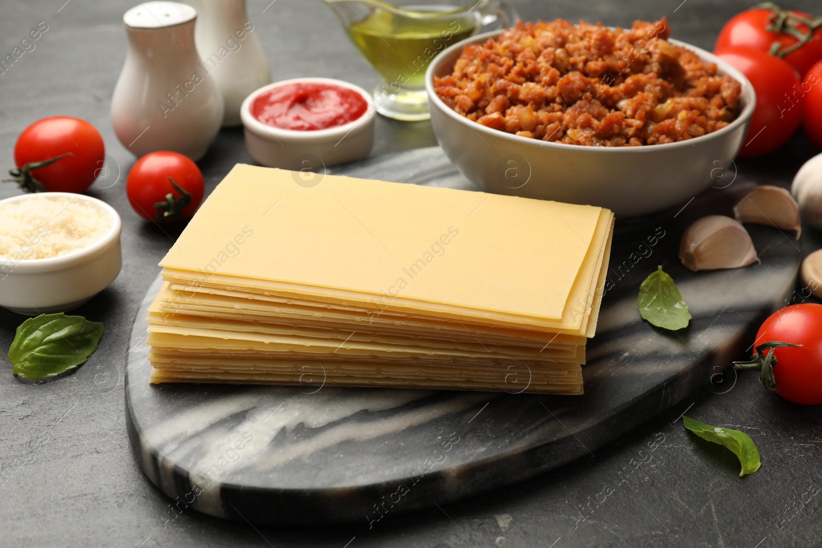 Photo of Products for cooking lasagna on dark textured table, closeup