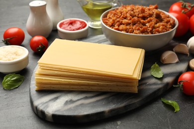 Products for cooking lasagna on dark textured table, closeup