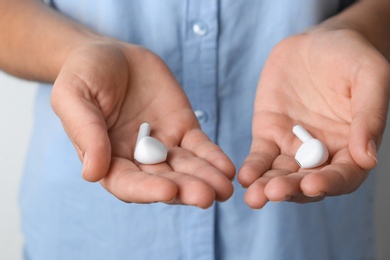 Photo of Woman holding pair of wireless earphones, closeup