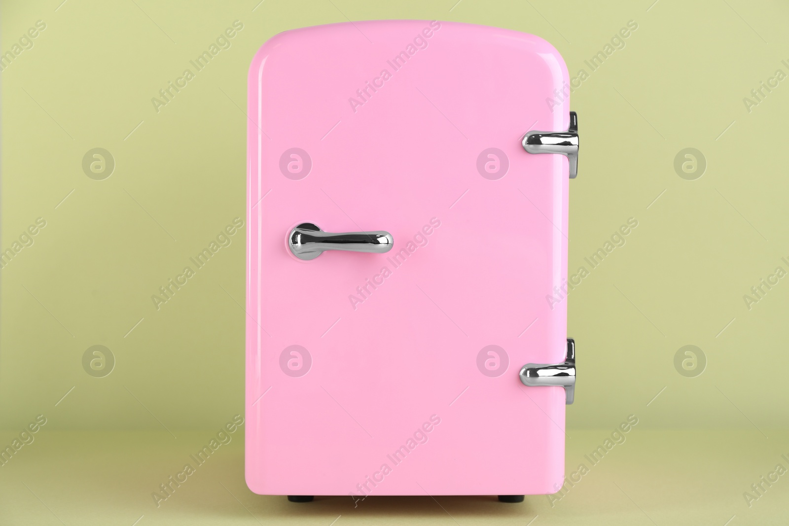 Photo of Mini refrigerator for cosmetics on light green background