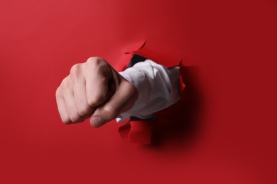 Photo of Businessman breaking through red paper with fist, closeup