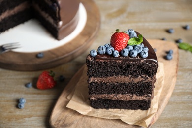 Piece of delicious chocolate cake decorated with fresh berries on wooden table