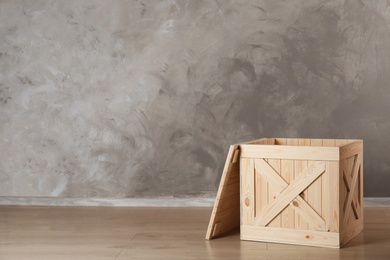 Photo of Wooden crate on floor against color background, space for text