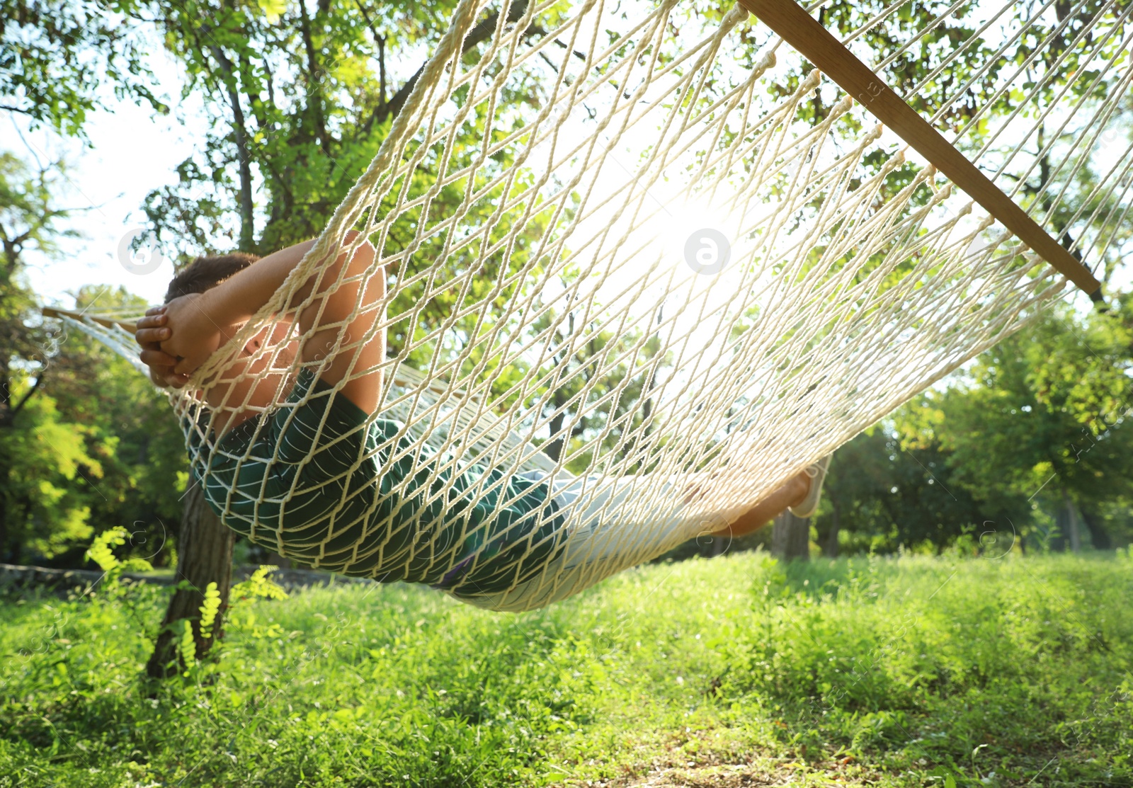 Photo of Young man resting in comfortable hammock at green garden