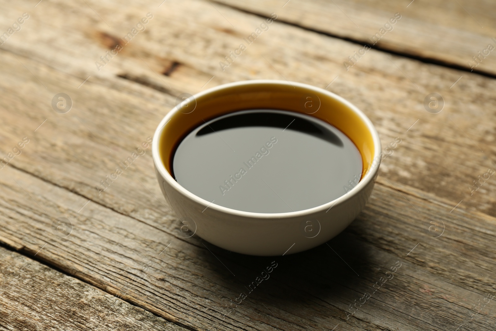 Photo of Soy sauce in bowl on wooden table