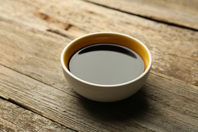 Photo of Soy sauce in bowl on wooden table