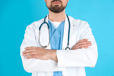 Mature doctor with stethoscope on blue background, closeup