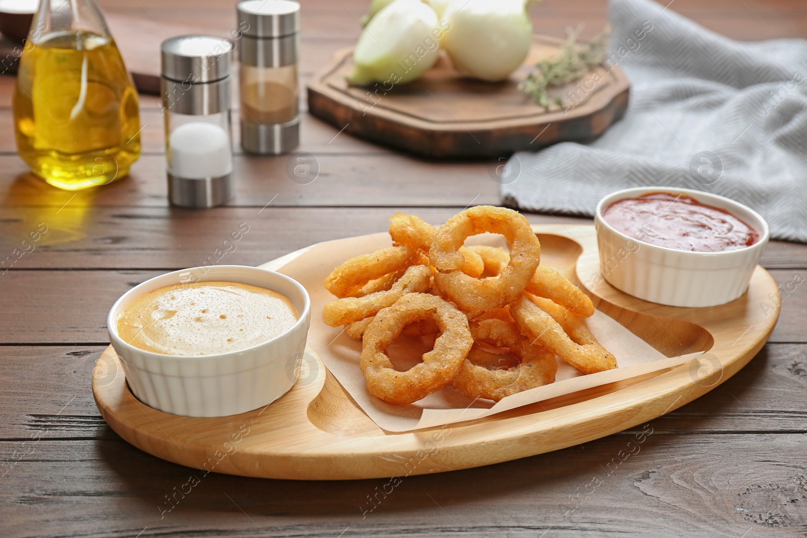 Photo of Plate with fried onion rings and sauces on table