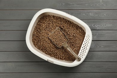 Photo of Cat litter tray with filler and scoop on grey wooden floor, top view