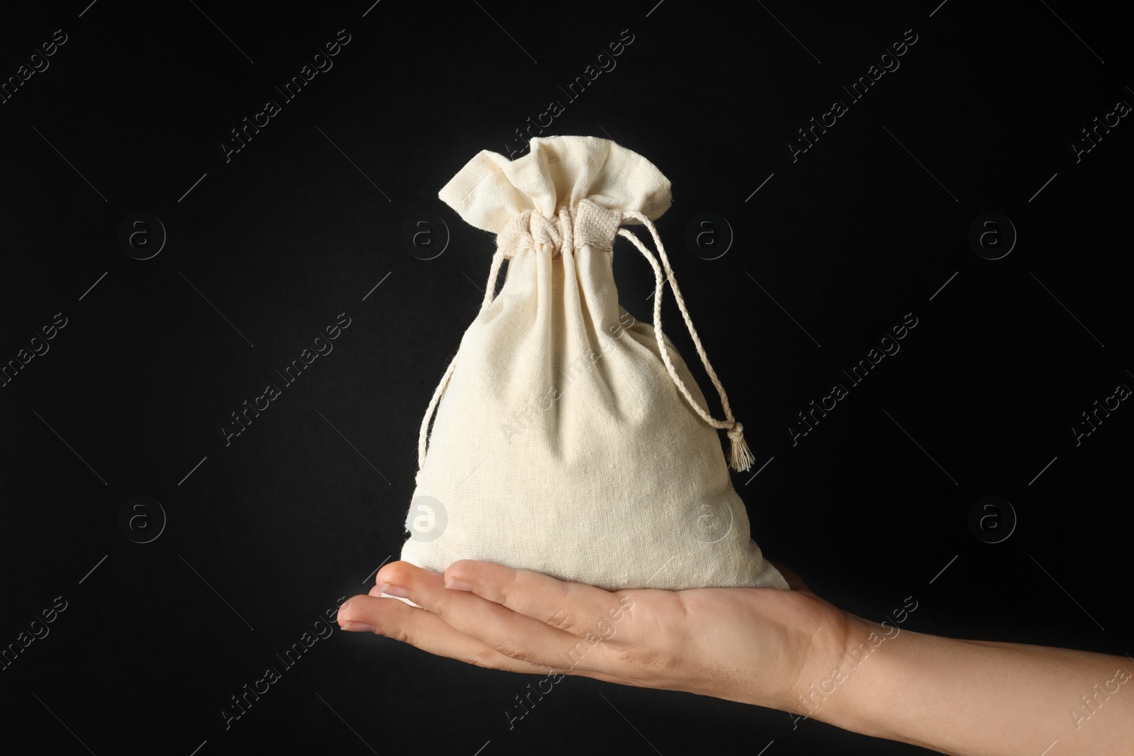 Photo of Woman holding full cotton eco bag on black background, closeup