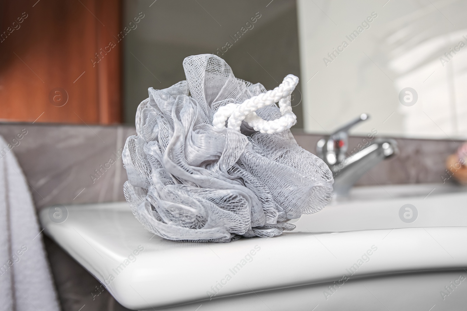 Photo of Grey shower puff on washbasin in bathroom, closeup