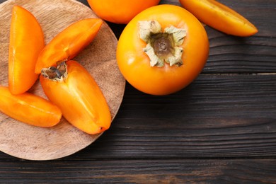 Delicious ripe persimmons on wooden table, top view. Space for text