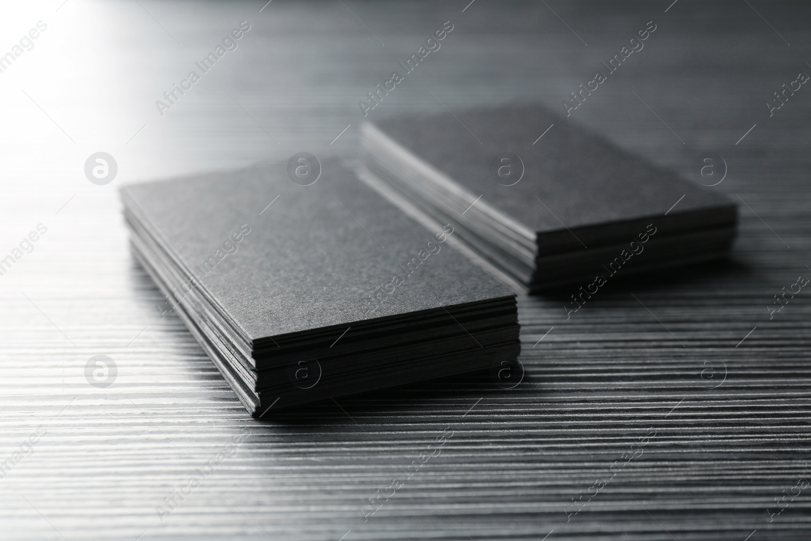 Photo of Blank black business cards on wooden table, closeup. Mockup for design