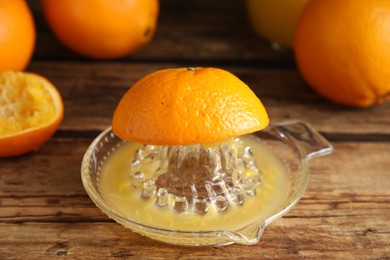 Cut fresh ripe orange and squeezer on wooden table, closeup