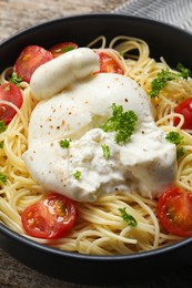 Photo of Delicious spaghetti with burrata cheese and tomatoes in bowl, closeup
