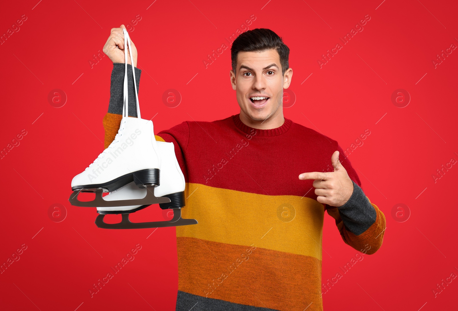 Photo of Emotional man with ice skates on red background