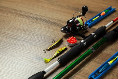 Spinning rods and fishing tackle on wooden background, closeup. Space for text