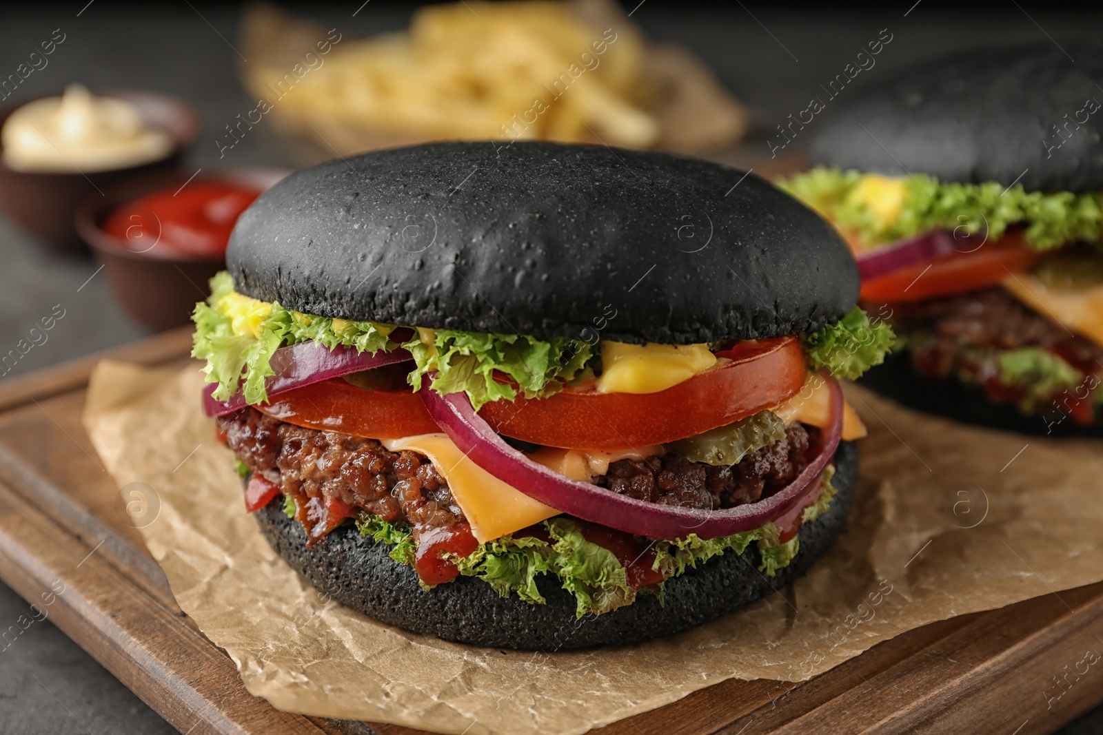 Photo of Board with black burgers on table, closeup