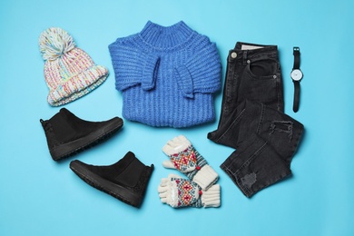 Flat lay composition with winter clothes and boots on light blue background