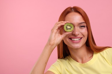 Photo of Happy woman covering eye with half of fresh kiwi on pink background, space for text