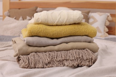 Stack of different folded blankets and clothes on bed. Home textile