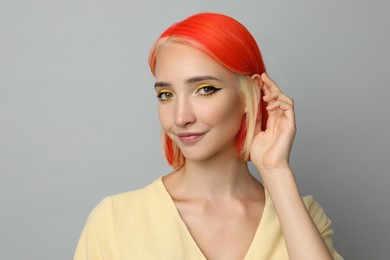Photo of Beautiful young woman with bright dyed hair on light grey background