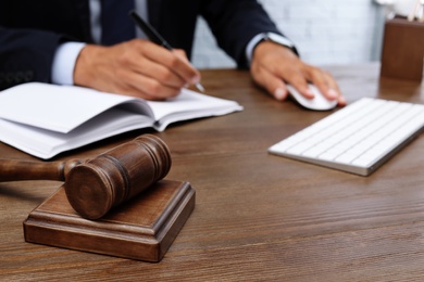 Wooden gavel and blurred lawyer on background. Notary services