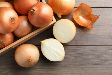 Photo of Whole and cut onions on wooden table, flat lay