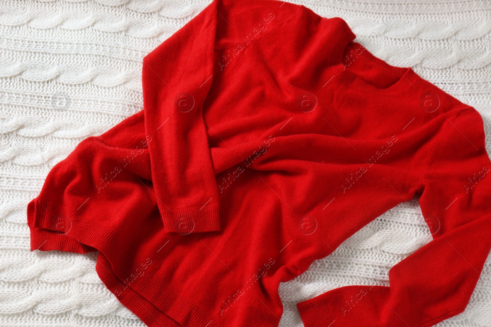 Photo of Red cashmere sweater on white knitted plaid