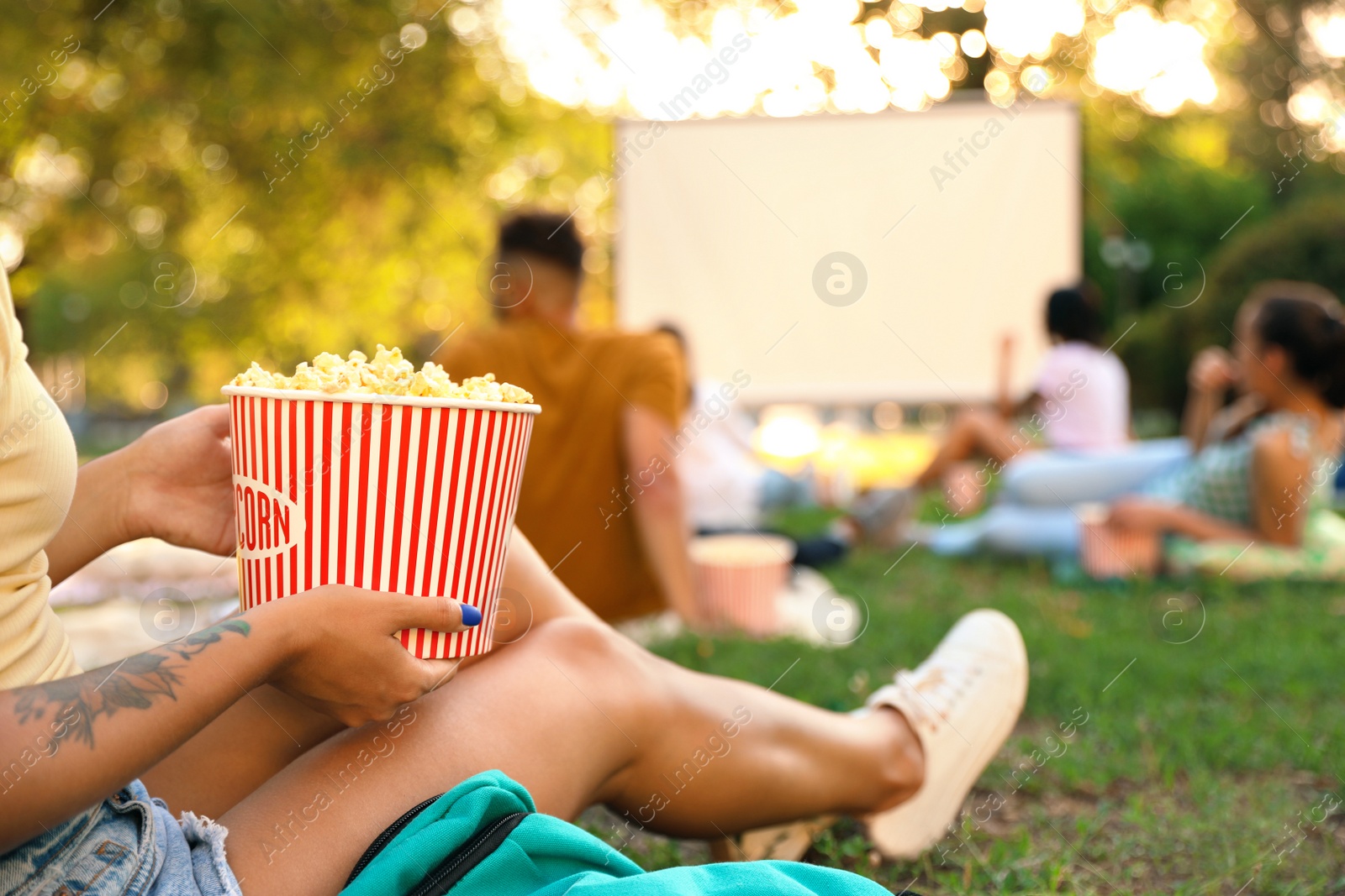 Photo of Young woman with popcorn watching movie in open air cinema, closeup. Space for text