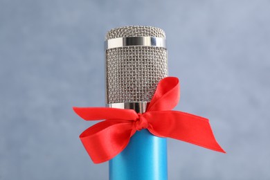 Photo of Microphone with red bow on grey background, closeup. Christmas music