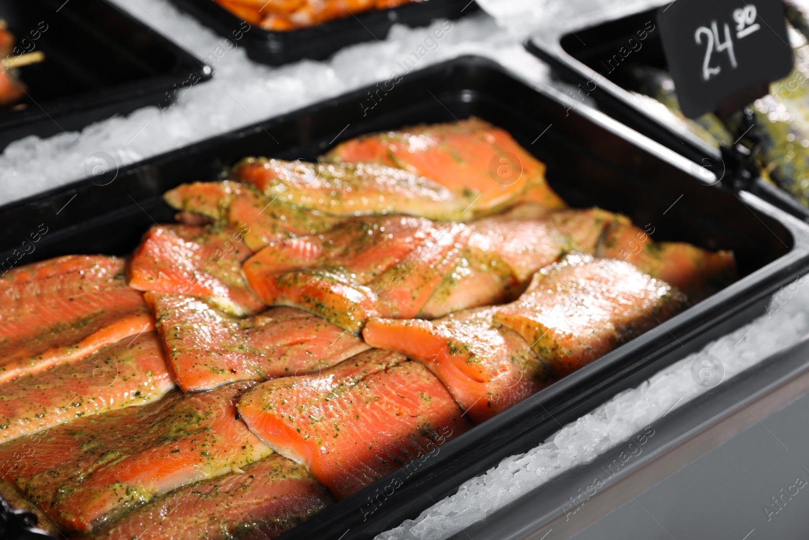 Photo of Fresh marinated fish in container on display, closeup