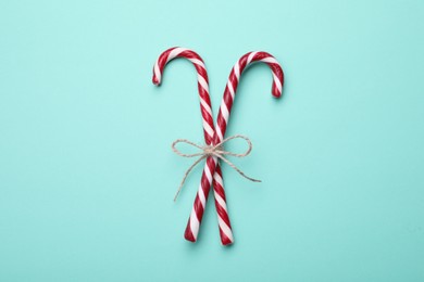 Photo of Two sweet Christmas candy canes with bow on turquoise background, top view