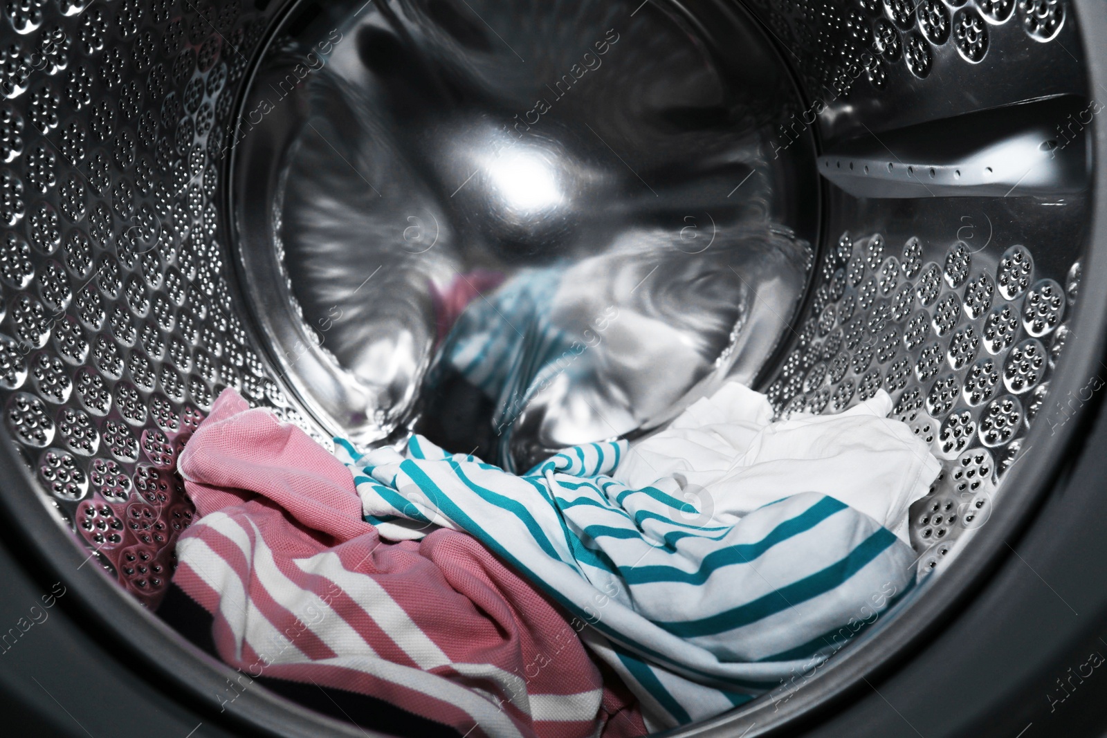 Photo of Modern washing machine drum with laundry, closeup