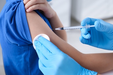 Doctor vaccinating little boy in hospital, closeup. Health care