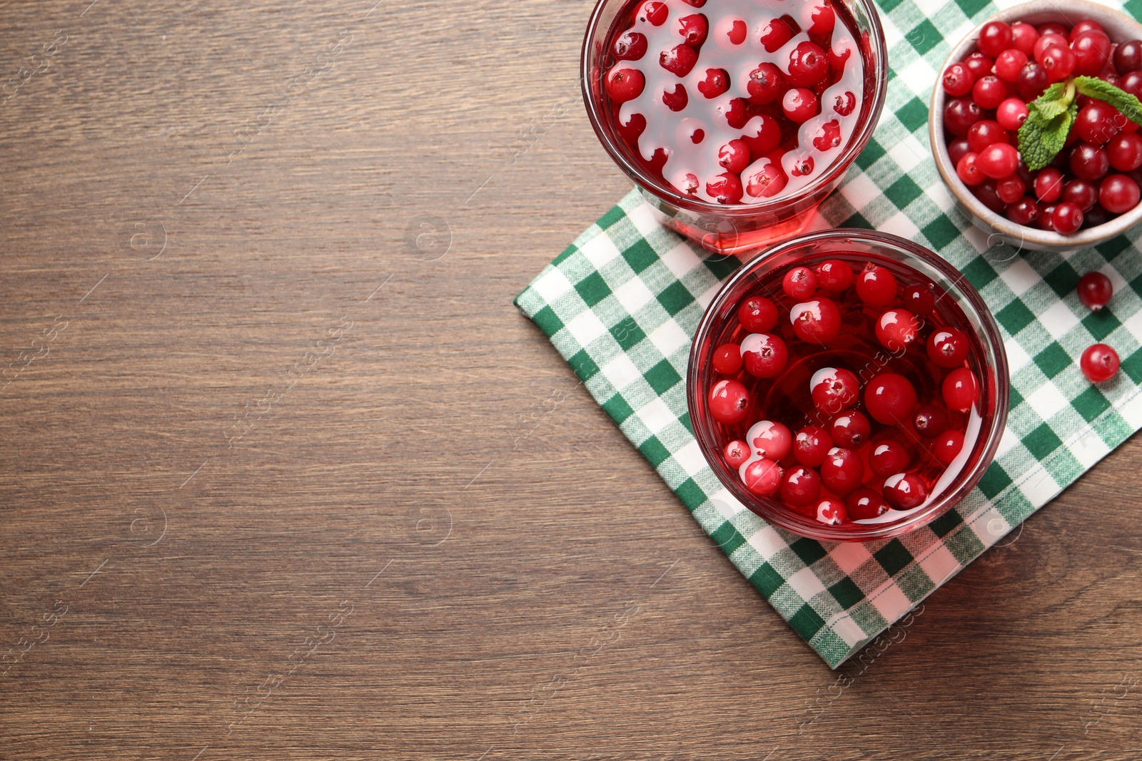 Photo of Tasty cranberry juice in glasses and fresh berries on wooden table, flat lay. Space for text