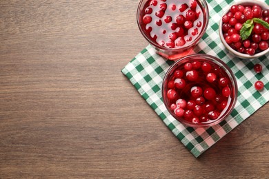 Tasty cranberry juice in glasses and fresh berries on wooden table, flat lay. Space for text