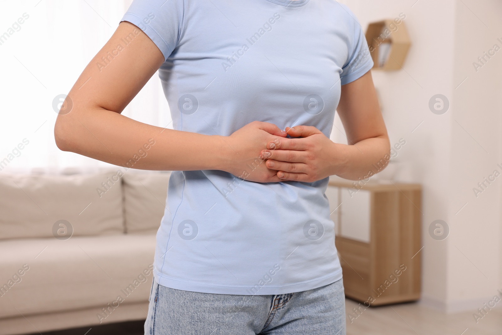 Photo of Woman suffering from abdominal pain at home, closeup. Unhealthy stomach
