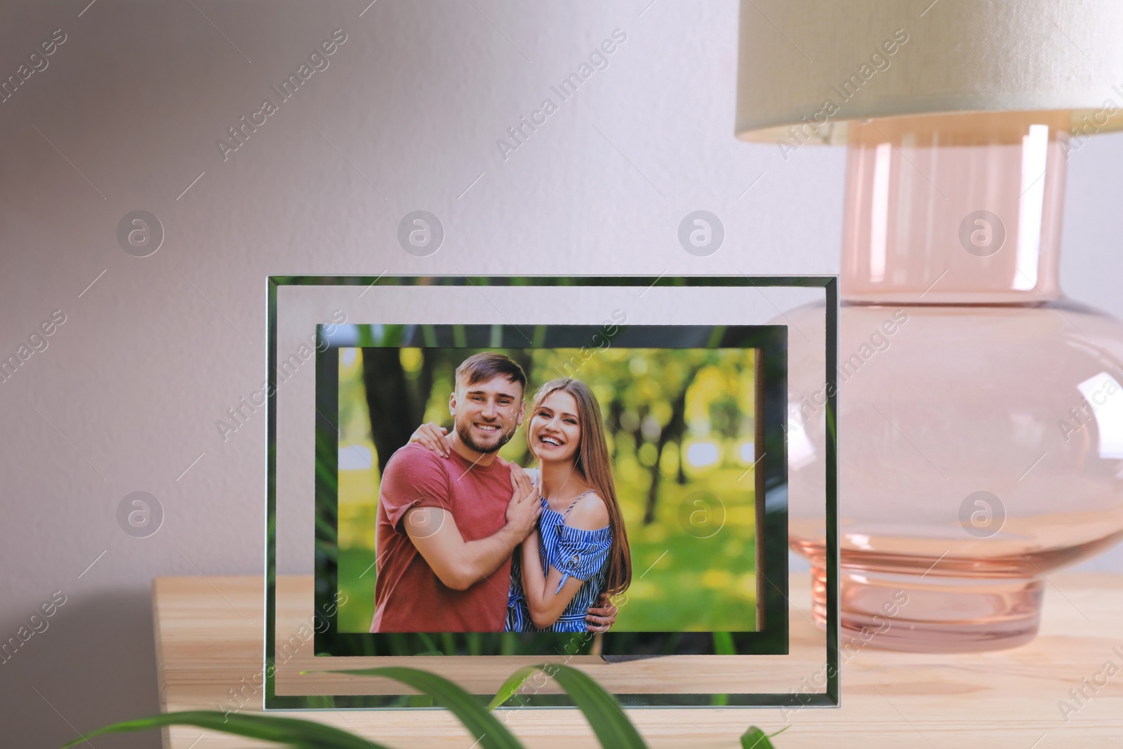 Photo of Frame with photo of young couple on wooden table indoors