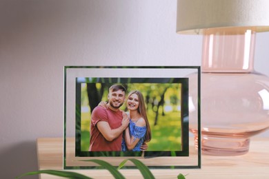 Photo of Frame with photo of young couple on wooden table indoors