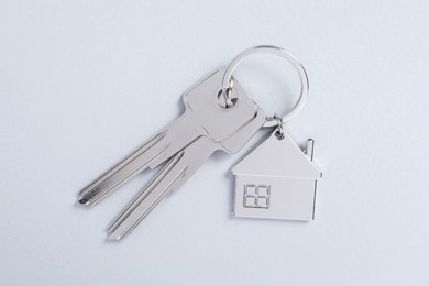 Photo of Keys with keychain in shape of house on light background, top view